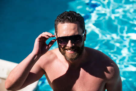 Summer pool resort. Handsome man at summer vacation. Man in sunglasses relaxing in swimming pool.の写真素材