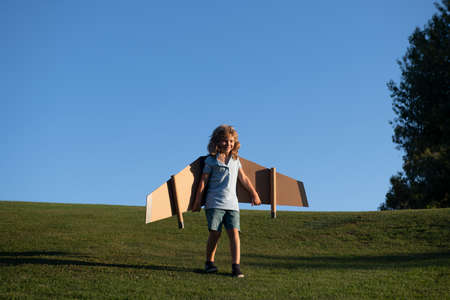 Child boy dreams and travels. Boy with airplane toy outdoors. Happy child playing with toy airplane...