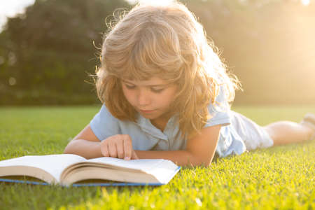 Child relax in the holiday. Kid read books on grass background.の写真素材