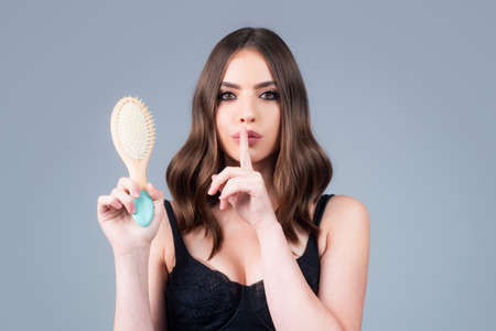 Woman is making hairstyle with comb. Beautiful young woman holding healthy and shiny hair, studio....