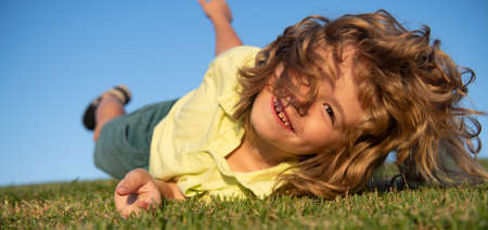 Happy child playing on green grass. Funny kid outdoor in spring garden. Children day concept.