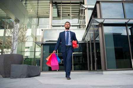 Business man doing shopping in the city. Portrait of businessman in suit with shopping bags.の写真素材
