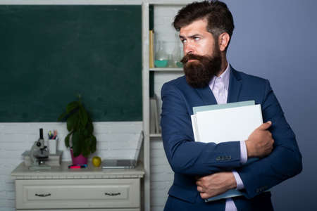 Portrait of confident caucasian male teacher in classroom. Man tutor or young professor.