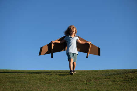 Child flying in plane made craft of cardboard wings. Dream, imagination, childhood. Travel and...