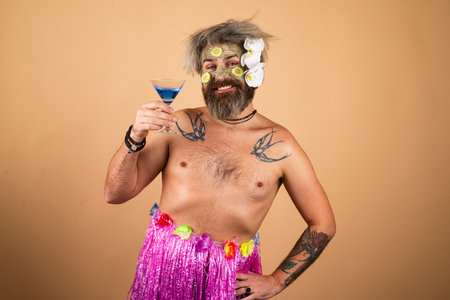 Funny man in hawaii. Male model with clay mask and cucumber slices on face. Man having cosmetic...