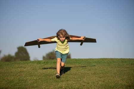 Child boy like a pilot with toy wings against blue sky. Kids freedom concept. Dreams of becoming a pilot. Kid pilot with toy jetpack playing outdoors. Happy childhood. Kids dreams.の写真素材