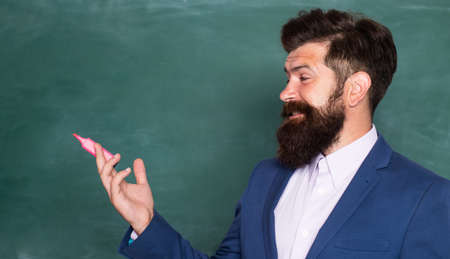 Closeup portrait of male teacher at school on blackboard with copy space.の写真素材