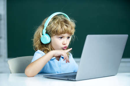 School kids with laptop computer and headphones in class at school.の写真素材