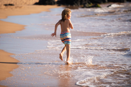 Active little boy splashing in the sea waves on a summer day during the holidays. The concept of family holidays with children.の写真素材