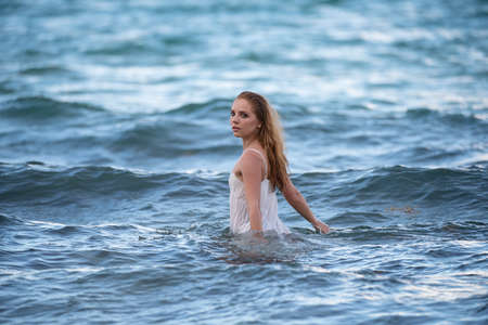 Young sexy woman is swimming in the transparent, blue sea. Sensual slim woman floating on the water...