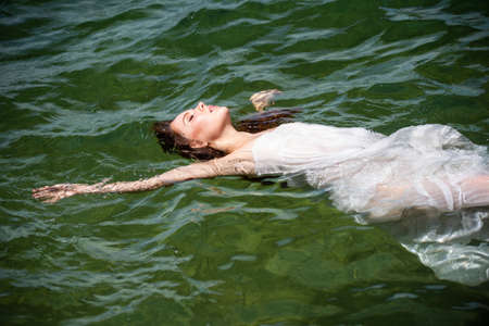 Young sexy woman is swimming in the transparent, blue sea. Sensual slim woman floating on the water of ocean water.の写真素材