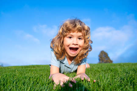 Portrait of a excited funny boy in the park. Funny little boy playing in garden backyard laughing and having fun. Summer outdoors activity for kids. Expression face.の写真素材