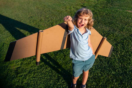 Kid leader and winner, success start up. Excited child boy play with toy jetpack wings superhero in park.の写真素材