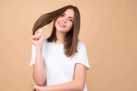 Young woman hairdresser with comb brushing hair. Brunette woman combing hair.