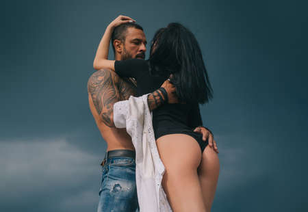 Romantic portrait of a sensual couple in love. Passionate man kissing sensual woman. Embrace and kiss. Loving couple hugging. Sexy lovers couple at blue sky background.の写真素材