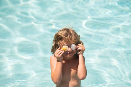 Swimming, summer vacation, lovely child boy playing in blue water. Covered eyes with shells.の写真素材