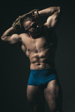 Healthy muscular young man with rope. Isolated on black background.の写真素材