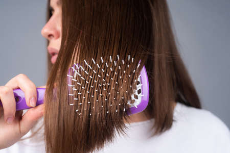 Close up woman brushing hair with comb. Beautiful girl with long hair hairbrush.