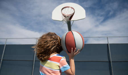 Cute little boy holding a basket ball trying make a score.の写真素材