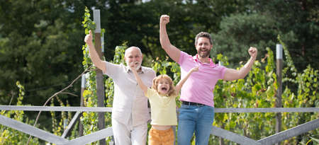 Excited family together with three different generations ages grandfather father and amazed son in spring garden.の写真素材