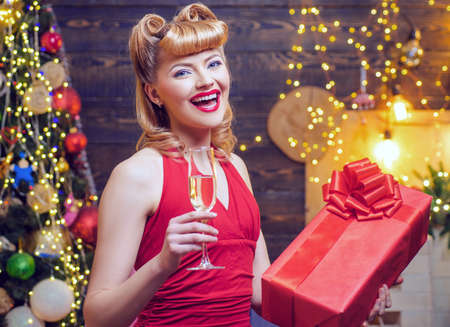 Beautiful retro woman with gift box at celebration party. Christmas celebration holiday. Beautiful girl with blond hair and red lips is holding a gift box.の写真素材