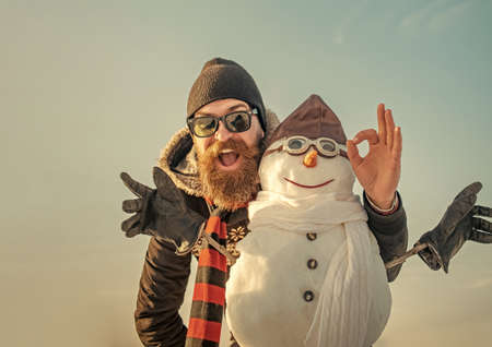Winter man with snowman in pilot hat. Christmas man with beard on happy face. Snowman pilot, winter holiday celebration.の写真素材