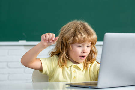 School child using digital pc laptop in class. Portrait of funny pupil of primary school study programming. Online learning technology, virtual education webinar.の写真素材