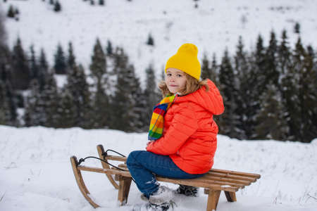 Boy kid enjoying a sleigh ride. Child on sleigh. Child plays outside in the snow. Winter, holiday and Christmas time.の写真素材