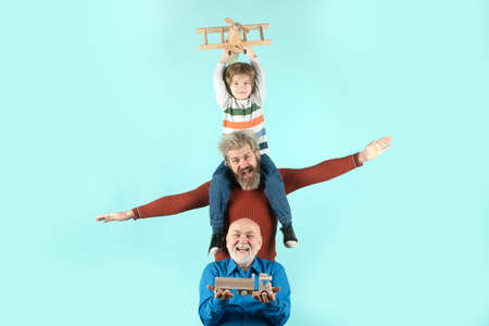 Three different generations ages grandfather father and child son playing with toy plane in studio. Journey travel trip concept. Isolated background. Men in different ages.の写真素材