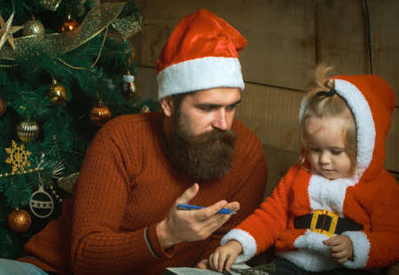 Santa father and baby son at Christmas tree. Winter family holiday and vacationの写真素材