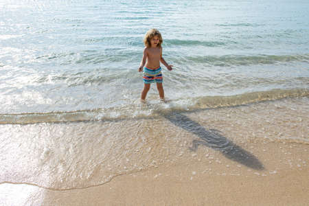 Child walking on the summer beach. Boy playing on the beach on summer holidays.の写真素材
