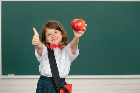 Cute little child with thumb up studying in classroom at elementary school. Back to school.
