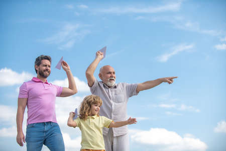 Men generation: grandfather father and grandson playing with toy plane outdoor on sky. Boy dreams of...