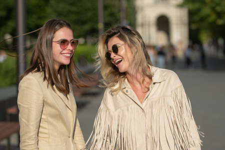Two excited happy women walking together on the street. High Fashion amazed model woman posing in...