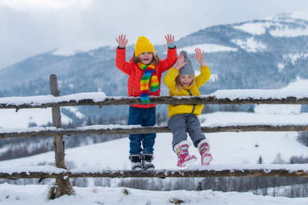Little girl and boy enjoying a day out playing in the winter forest. Children siblings having fun in beautiful winter park. Happy childhood.の写真素材