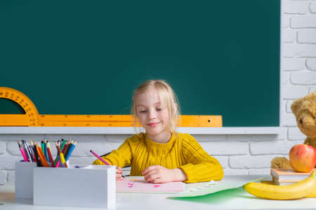 Cute little school kid girl study in a classroom. Education, learning and children concept.の写真素材