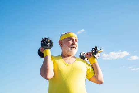 Elderly man after her workout. Healthcare cheerful lifestyle. Senior man exercising on blue sky....