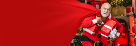 Criminal Santa Claus posing with a bag of christmas gifts. Criminal christmas. Funny bad Santa Claus with gift. Horizontal banner for website design. Web banner header, copy space.の写真素材