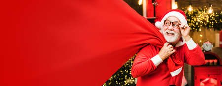 Happy Santa dressed in winter clothing think about Christmas near Christmas tree. Horizontal banner for website design. Web banner header, copy space.の写真素材