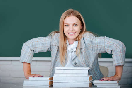 Female happy college student holding book in classroom, preparing for exam.