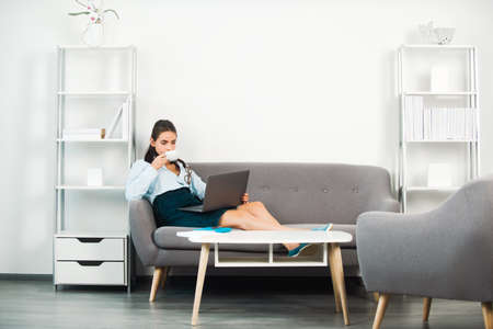 Break time concept. Business woman entrepreneur drinking coffee working in office, professional employee at workplace. Young beautiful secretary girl.の写真素材