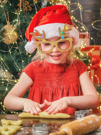 Funny kids are preparing the dough playing with flour in the kitchen. Funny child girl are preparing gingerbread for Christmas.の写真素材
