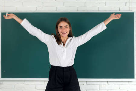 Student excited amazet student with raised hands holding chalk in school classroom on blackboard background.の写真素材