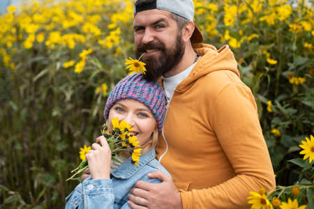 Young lovers hugging and embracing in autumn park with flovers. Couple in love tenderness and...