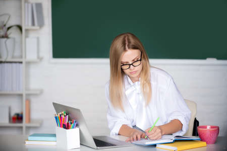 Portrait of young female college student studying in classroom preparing for test or exam in class with blackboard background.の写真素材