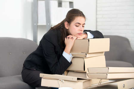 Sad busy secretary, stressed overworked business woman and folders with the documents too much work, office problem. Tired stressed employee at workspace.の写真素材