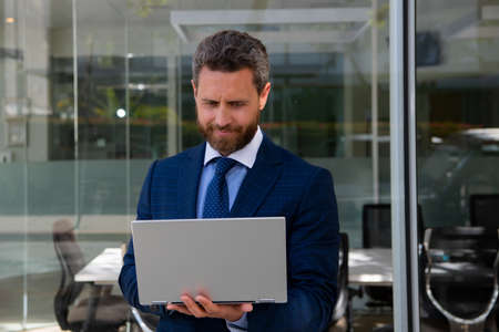 Portrait of handsome businessman using laptop outdoor.の写真素材
