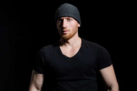 Confident attractive man with serious face on black.
