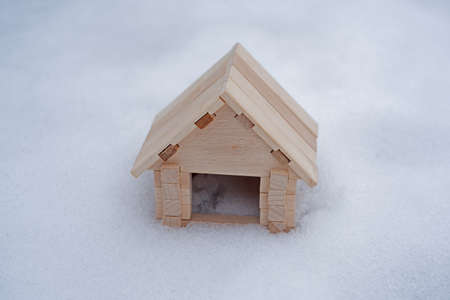 Toy wooden house in winter snow forest. Small wooden house in winter on a background of snow. Winter discounts for home purchases.の写真素材