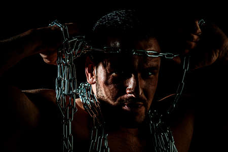 Portrait of handsome man with serious face break the chain. Shadow male face.
